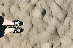 feet in polka dots shoes on the sand in desert