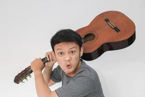 Angry Young Asian man musician with guitar to punch photo