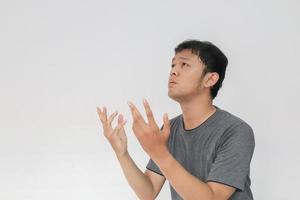 Young Asian man in gray t-shirt praying with sad face photo