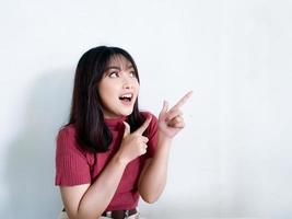 Happy and smile face with smile of young Asian girl in red shirt with hand point on empty space. photo