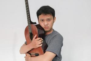 Young Asian musician who is sad by hugging his guitar photo