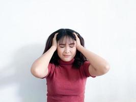 retrato de una mujer joven estresada sosteniendo la cabeza en las manos con el fondo. niña asiática infeliz con expresión de cara preocupada y estresada mirando hacia abajo. foto