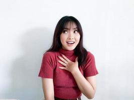Wow and shocked face of beautiful Young Asian girl with hand touching chest wear red shirt. Advertising model concept. photo