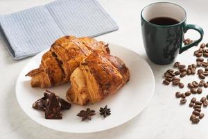 delicious, crispy croissants, chocolate, hot coffee in the blue cup and kitchen towel on plate on marble table