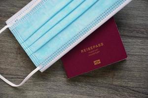 german passport reisepass and medical face mask - travel during corona covid-19 pandemic concept photo