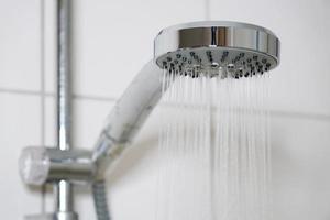 ducha con cabezal de ducha moderno y agua corriente en el baño foto