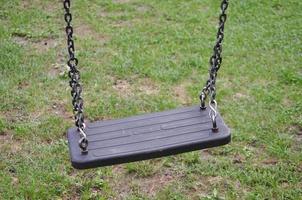 A swing suspended on chains in a playground on the grass photo