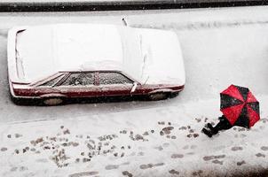 Woman holding a black and red umbrella under snow photo