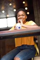 Smiling black girl with very short hair drinking a cocktail in an urban cafe. photo