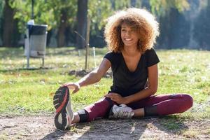 Fitness black woman runner stretching legs after run photo