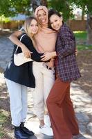 Delighted young diverse girls embracing and smiling in park photo