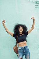 Funny black woman with afro hair raising arms outdoors photo