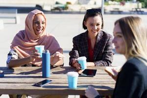 mujeres diversas felices tomando café y charlando al aire libre foto