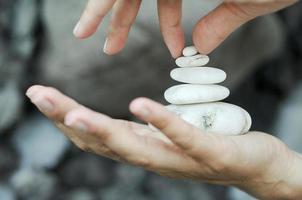 piedras blancas apiladas en las manos de una mujer como actividad de relajación foto