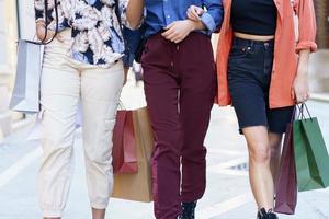 Crop anonymous trendy women walking on street with shopping bags photo