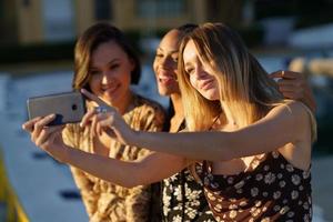 Encantadoras novias diversas tomando selfie en smartphone foto