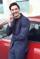 Young businessman talking with his mobile phone near a car photo