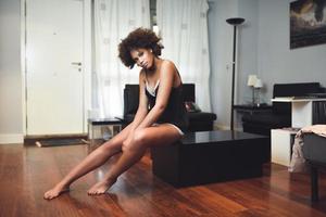 Black topless woman with afro hairstyle sitting in a couch photo