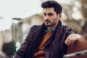 Thoughtful young man sitting on an urban bench. photo