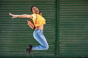 Young black woman jumping on blinds background. photo