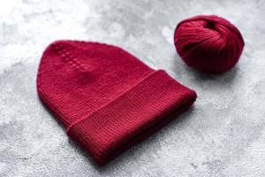 Red warm knitted women's hat on a concrete background photo