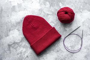 Red warm knitted women's hat on a concrete background photo