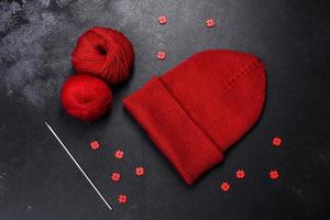 Red warm knitted women's hat on a concrete background photo