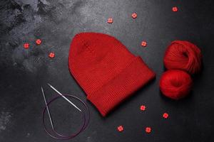 Red warm knitted women's hat on a concrete background photo