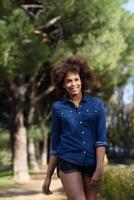 joven negra con peinado afro caminando en un parque urbano foto