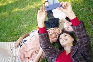mujeres alegres y diversas tomando selfie en el césped foto