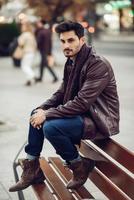 Thoughtful young man sitting on an urban bench. photo