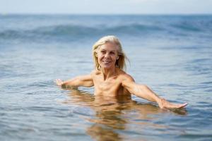 Eldery woman in good shape bathing in the sea. photo