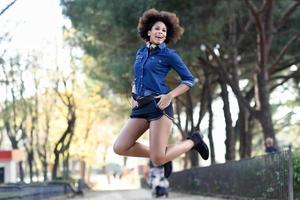 Young black woman with afro hairstyle jumping in urban background photo