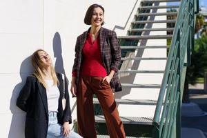 Delighted young women smiling while resting near stairs in park photo