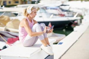 Mature sporty woman taking a break to check a fitness app on her smartphone photo