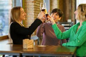 Excited women proposing toast near pub window photo