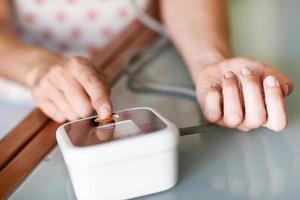 Woman measuring her own blood pressure at home. photo