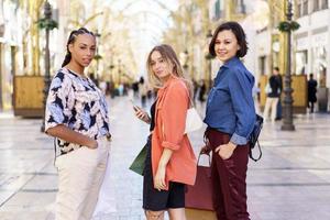 Multiracial female friends standing on city street with purchases photo