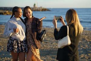 Anonymous woman taking photo of girlfriends on shore