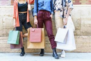 Crop fashionable women with paper bags standing on street after shopping photo