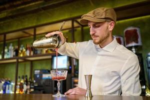 Barman pouring cocktail into glass photo