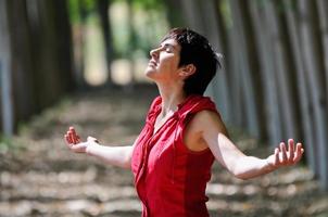 Woman dressed in red, meditating in the forest photo