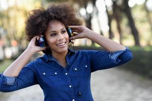 joven mujer negra, peinado afro, en la calle urbana con auriculares 4900150  Foto de stock en Vecteezy