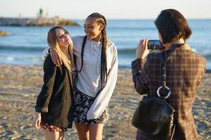 Woman taking photo of diverse girlfriends on beach