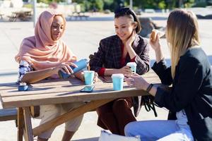 mujeres diversas positivas tomando café en la mesa en el parque