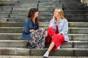 dos mujeres jóvenes hablando y riendo en pasos urbanos foto