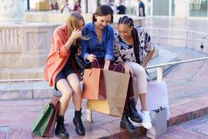 mujeres multirraciales de moda verifican las compras después de ir de compras en la ciudad foto