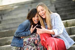 dos mujeres mirando algo divertido en su teléfono inteligente foto