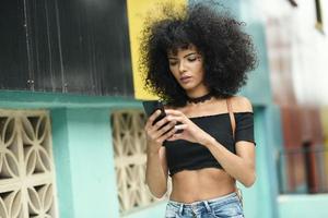 Black woman afro hair on the street holding a smartphone photo