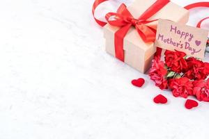concepto del día de las madres idea de caja de regalo hecha a mano desea fotografía - hermosos claveles florecientes con caja de lazo de cinta roja aislada en un escritorio de mármol moderno, primer plano, espacio de copia, maqueta foto